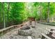 Cozy fire pit area with seating and wood storage, surrounded by lush greenery at 677 Juliette Ct, Creedmoor, NC 27522