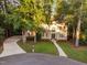 Aerial view of the two-story brick home with a circular driveway and lush, mature trees adding privacy and beauty at 7808 Umstead Forest Dr, Raleigh, NC 27612