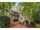 View of the beautiful backyard and deck of this home, surrounded by mature trees and a stone retaining wall at 7808 Umstead Forest Dr, Raleigh, NC 27612