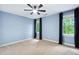 Bedroom with a ceiling fan, carpet floors, blue walls, and updated windows at 7808 Umstead Forest Dr, Raleigh, NC 27612