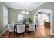 Elegant dining room with a stylish chandelier, an arched entry, and a view to the home's kitchen at 7808 Umstead Forest Dr, Raleigh, NC 27612
