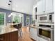 Kitchen with granite countertops, stainless appliances, a center island with seating, and views from several windows at 7808 Umstead Forest Dr, Raleigh, NC 27612