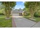 Landscaped front yard with mature trees framing a charming home with a brick and siding exterior at 8517 Evans Mill Pl, Raleigh, NC 27613