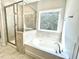 Bright bathroom features a soaking tub with window, walk-in shower, and neutral tile at 8813 Moss Glen Dr, Raleigh, NC 27617