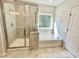 Bright bathroom features a walk-in shower, soaking tub, and neutral tiling at 8813 Moss Glen Dr, Raleigh, NC 27617