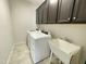 Laundry room featuring a washing machine, dryer, dark cabinets, and sink at 8813 Moss Glen Dr, Raleigh, NC 27617