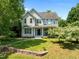 Beautifully landscaped home with a manicured lawn, stone wall, and a variety of trees under a clear blue sky at 100 Michaels Way, Chapel Hill, NC 27516