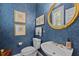Elegant powder room with blue wallpaper, gold framed mirror, and pedestal sink at 1009 Bearglades Ln, Raleigh, NC 27615