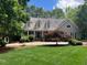 Inviting home exterior features a lush front lawn, mature trees, and a charming covered porch at 1009 Bearglades Ln, Raleigh, NC 27615