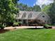 Inviting home exterior features a lush front lawn, mature trees, and a charming covered porch at 1009 Bearglades Ln, Raleigh, NC 27615