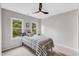 Bright bedroom with a ceiling fan, two windows overlooking mature trees, and a cozy bed with striped bedding at 107 Ivy Hollow Ct, Morrisville, NC 27560