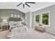 Comfortable main bedroom with a padded headboard, carpet, a bench, large windows overlooking mature trees, and ceiling fan at 107 Ivy Hollow Ct, Morrisville, NC 27560