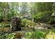 Backyard pond featuring a unique fountain and lush green landscaping with a home in the background at 107 Silo Dr, Chapel Hill, NC 27514