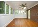 Inviting sunroom with hardwood floors, a ceiling fan, brick accent wall, and plenty of natural light at 107 Silo Dr, Chapel Hill, NC 27514