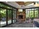 Inviting sunroom featuring a stone fireplace, ample natural light, and serene wooded views at 107 Silo Dr, Chapel Hill, NC 27514