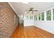 Spacious sunroom with brick walls, hardwood floors, a ceiling fan, and multiple windows for natural light at 107 Silo Dr, Chapel Hill, NC 27514