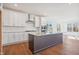 Spacious kitchen with a large island, stainless hood, white cabinetry, and hardwood floors at 11 Little Gem Ln, Fuquay Varina, NC 27526