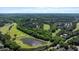 Aerial shot of a golf course and a serene pond surrounded by lush greenery and blue skies at 1132 Heritage Knoll Dr, Wake Forest, NC 27587