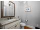 Powder room featuring a granite countertop, classic mirror, and hardwood floors at 1132 Heritage Knoll Dr, Wake Forest, NC 27587