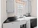 Functional laundry room boasts modern washer and dryer units, sink and custom cabinetry at 115 Nuttree Way, Durham, NC 27713