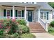 Inviting front porch with brick steps, white railings, decorative door, and manicured flowerbeds at 119 Marykirk Pl, Garner, NC 27529