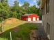 View of a new red metal barn featuring multiple garage doors and a gravel parking area at 121 Pheasant Ct, Pittsboro, NC 27312