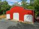 Newly built red metal barn with three garage doors, gravel parking, and eagle weathervane at 121 Pheasant Ct, Pittsboro, NC 27312