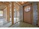 Unfinished entryway with a wooden door, exposed studs, and subflooring at 121 Pheasant Ct, Pittsboro, NC 27312