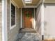 A covered entrance with wooden door, gravel floor and mixed siding textures at 121 Pheasant Ct, Pittsboro, NC 27312