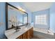 Spacious bathroom with blue walls, a large vanity, a soaking tub, and a window for natural light at 12501 Garden Tree Ln, Raleigh, NC 27614