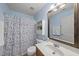 Bathroom with blue walls, shower with a polka-dot curtain, vanity, toilet, and wall storage cabinet at 12501 Garden Tree Ln, Raleigh, NC 27614