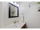 Bathroom with a vanity featuring a square mirror, modern fixtures, and a glass shelf at 12501 Garden Tree Ln, Raleigh, NC 27614