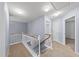Upstairs hallway with plush carpet, white wood railing, and neutral paint at 12501 Garden Tree Ln, Raleigh, NC 27614