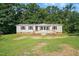 Charming single-story home with tan siding and a wooden porch, nestled among lush green trees at 1392 L Cooper Rd, Cameron, NC 28326