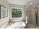 Bathroom with a soaking tub, tile shower, and garden window overlooking lush greenery at 1404 Kings Lassiter Way, Raleigh, NC 27614