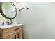 Bathroom vanity with wood cabinets, bronze hardware, a round mirror and light green paint at 1408 Old Ivey Rd, Apex, NC 27523