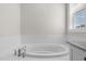 A relaxing soaking tub is set beneath a window in this bright bathroom at 1423 Tannin Dr, Durham, NC 27713