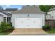 Attached garage with white doors and updated exterior lighting and landscaping at 1423 Tannin Dr, Durham, NC 27713
