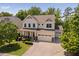 An aerial view of a charming two-story home featuring a manicured lawn and attached two-car garage at 1458 Wragby Ln, Apex, NC 27502