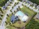 Aerial view of community pool, pool house, lounge furniture, playground and parking lot at 1458 Wragby Ln, Apex, NC 27502