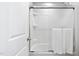 A bright white bathroom featuring a shower over tub with glass enclosure and a towel on the rack at 1458 Wragby Ln, Apex, NC 27502