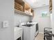 Bright laundry room with white washer and dryer, utility sink, and built-in shelving at 1458 Wragby Ln, Apex, NC 27502