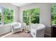 Bright sitting area with three windows overlooking a vibrant green view and two plush white chairs at 1458 Wragby Ln, Apex, NC 27502
