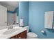 Bathroom with blue walls, a white toilet, and a vanity with a white sink and dark wooden cabinets at 19 Arch Oak Ct, Clayton, NC 27527