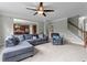 Cozy living room with plush blue sectional, staircase, ceiling fan, and open access to kitchen at 19 Arch Oak Ct, Clayton, NC 27527