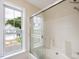 Bright bathroom features bathtub with sliding glass doors and large window with backyard view at 1928 Shadow Glen Dr, Raleigh, NC 27604