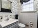 Compact bathroom featuring white tile, grey vanity, and stylish patterned wallpaper at 1930 Reid St, Raleigh, NC 27608