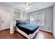 Comfortable bedroom with hardwood floors, built-in shelving, a ceiling fan, and large window at 2 Donnelly Ct, Durham, NC 27713