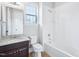 Bathroom with tiled tub, brown vanity, white walls, and natural light from the window at 203 S South Bend Dr, Durham, NC 27713