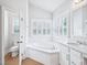 Bathroom featuring a large soaking tub, double windows and white marble countertop at 203 S South Bend Dr, Durham, NC 27713